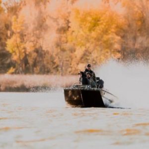 three men driving across a lake on aluminum boat